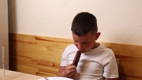 A boy is sitting at a table and eating ice cream for dessert.
