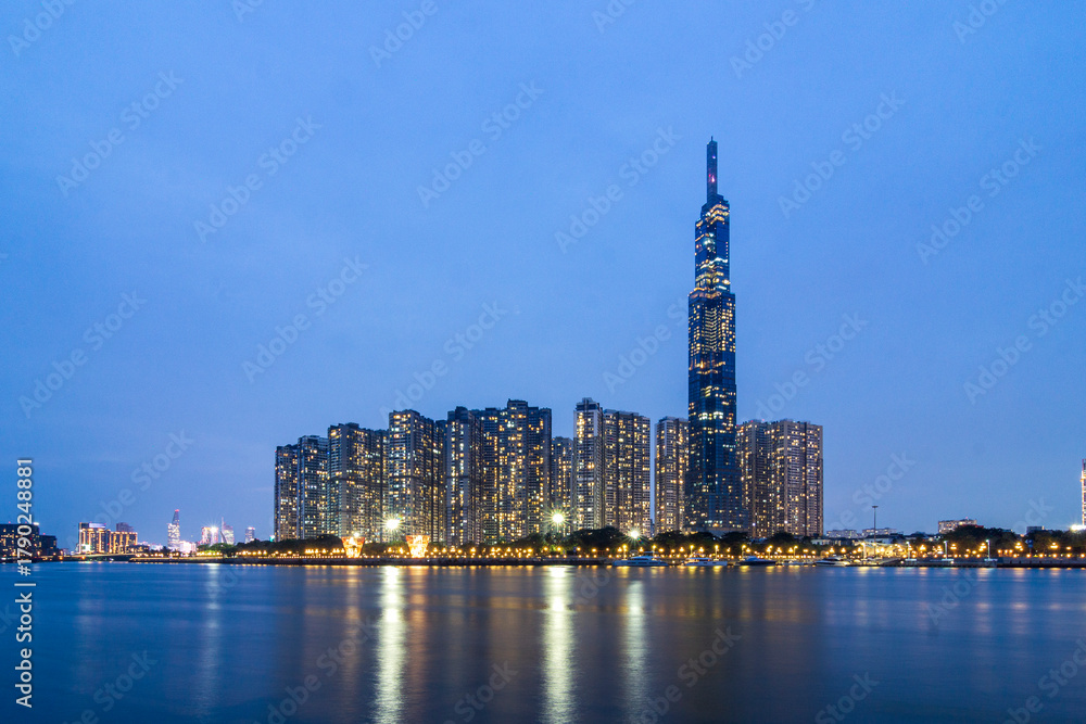 Obraz premium Saigon, Vietnam - 11 Nov, 2025 - Evening skyline view of Landmark 81 and surrounding high-rise buildings reflecting on the Saigon River in Binh Thanh District.