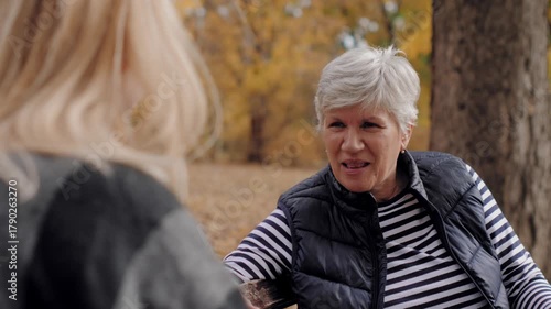 Elderly mother laughing and talking with daughter outdoors