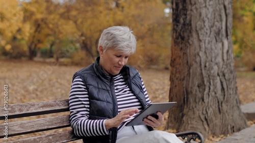 Senior woman using digital tablet in autumn park