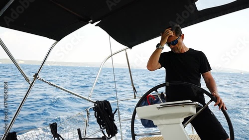Man standing at the helm of a sailing yacht near Croatia, steering the boat through open water. Leadership, control, sailing lifestyle and freedom at sea.