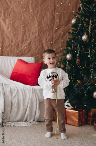 a little boy playing near a Christmas tree