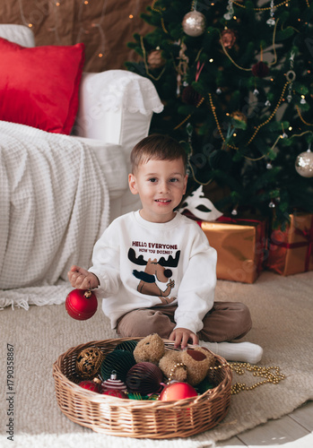a little boy playing near a Christmas tree