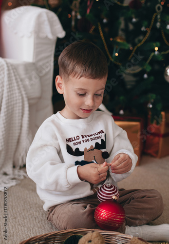 a little boy playing near a Christmas tree