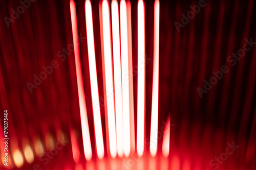 Abstract blurred vertical red light streaks on a dark background.