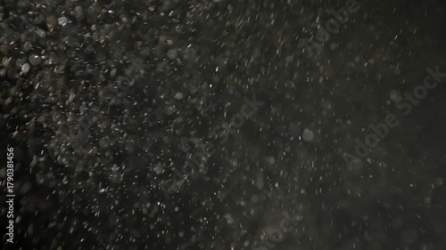 Soft pollen and dust particles floating in the air, illuminated by cold light beams, creating dreamy abstract bokeh on a dark background. 4K macro footage with gentle motion and selective focus.