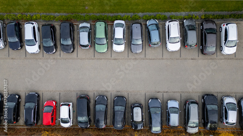 Aerial view showcases neatly aligned cars in a parking lot with diverse vehicle colors and sizes.