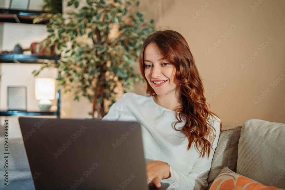 Fototapeta premium Young caucasian woman working or talking on laptop from home