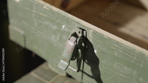 Man opens an empty old military ammunition box and slams the lid shut, raising a cloud of dust. Vintage green crate with worn paint and metal latch in dramatic warm light. 4K footage.