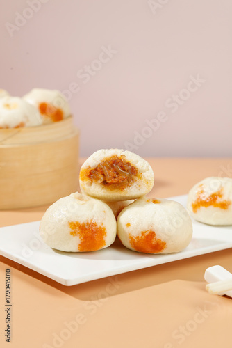 Traditional Chinese Xiaolongbao Steamed Buns with Golden Egg Yolk Filling on White Plate