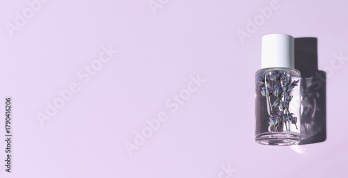 Glass bottle with lavender tonic on purple background with copy space