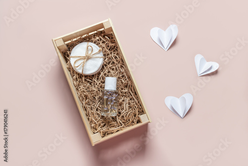 Wooden gift box with reusable cotton pads and lavender tonic on pastel pink background