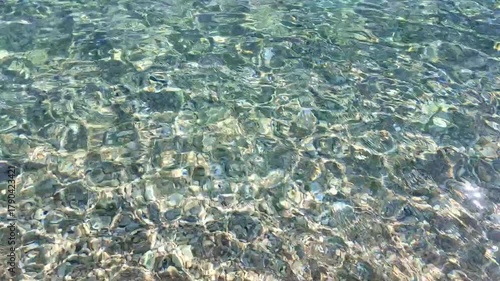 Crystal clear waves glistening in sunlight  gentle ocean ripples on sandy beach