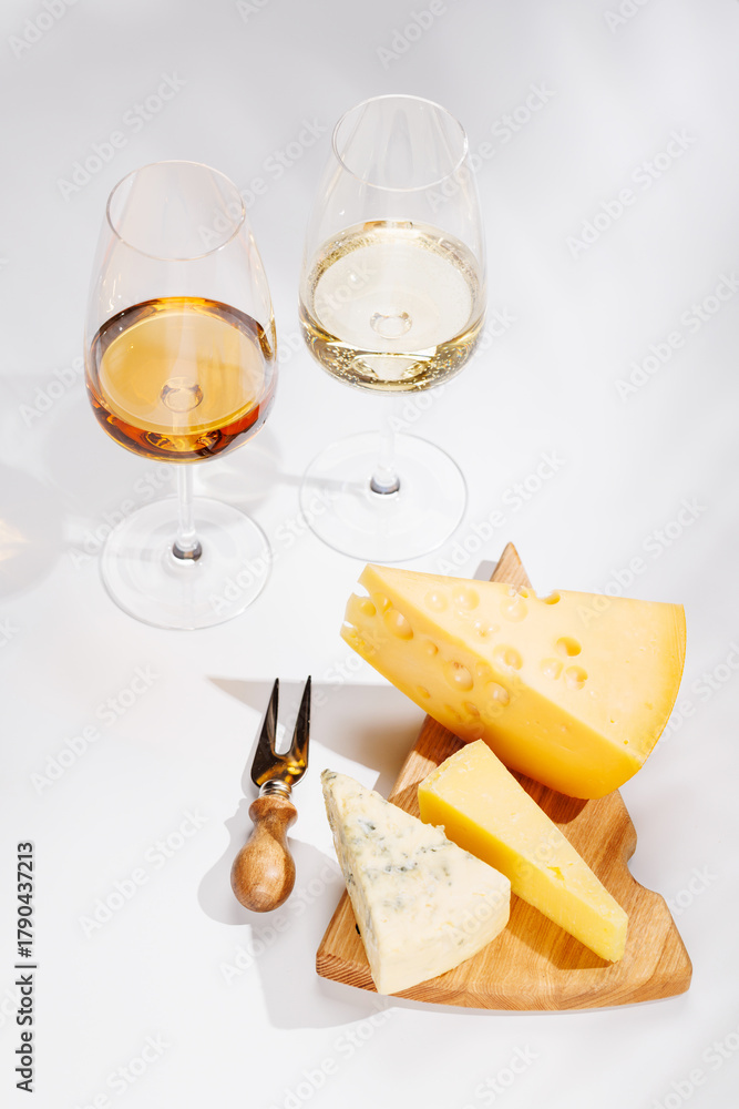Naklejka premium Assorted cheeses and wine glasses on white background