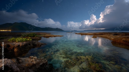 Fototapeta Naklejka Na Ścianę i Meble -  Tranquil tropical seascape under a dramatic night sky with stars and illuminated clouds over a coral reef