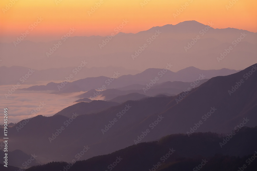 Fototapeta premium Serene mountain landscape at sunrise with soft orange sky and misty valleys