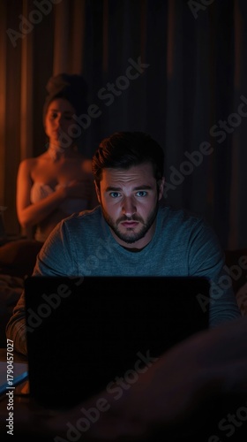 Man focused on laptop late at night with moody lighting