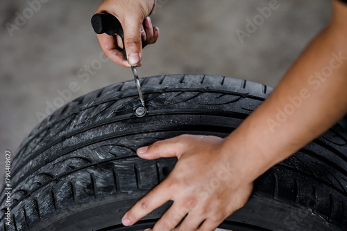 A mechanic is removing a nail from a tire so that the tire can be repaired and restored to full usability.