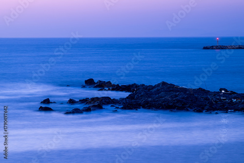 Serene seascape at dusk with rocky shoreline and calm waters
