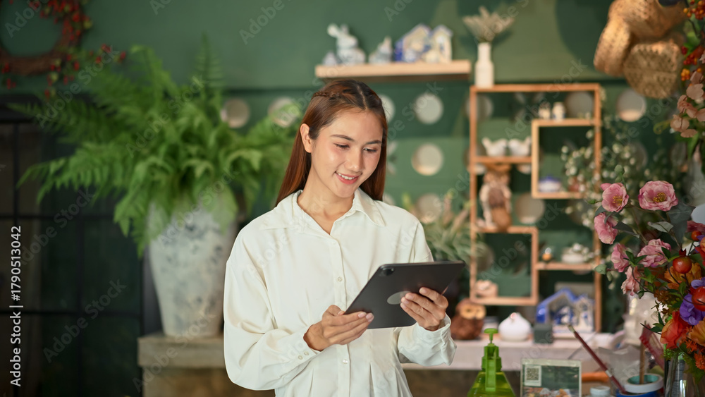 Fototapeta premium Florist woman business owner managing flower stock with a digital tablet