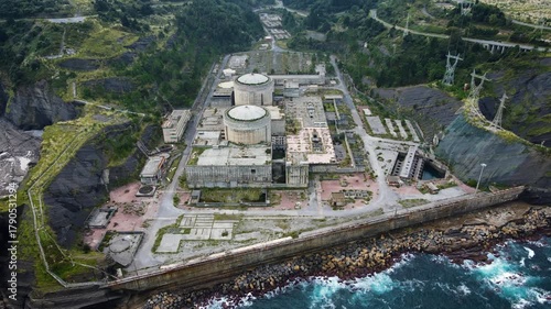 Aerial drone view of the abandoned Lemoiz nuclear power plant ruins on the Basque Country coast, Spain. The unfinished industrial complex with twin reactor domes sits between cliffs and the sea