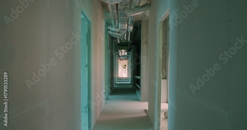 Raw corridor of a new office building during finishing phase, with exposed drywall and ventilation visible.