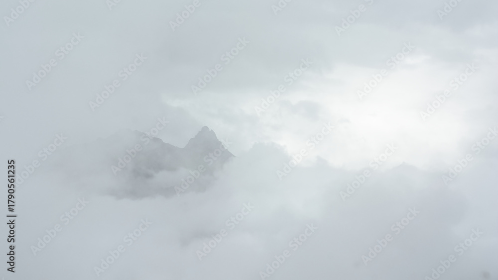 Naklejka premium Alpine granite mountain peak covered in mist and clouds. La Vanoise national park, Savoie, France 