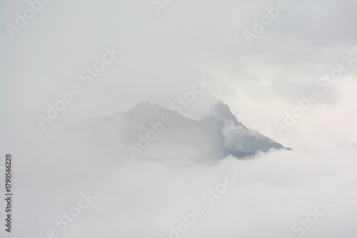 Alpine granite mountain peak covered in mist and clouds. La Vanoise national park, Savoie, France 