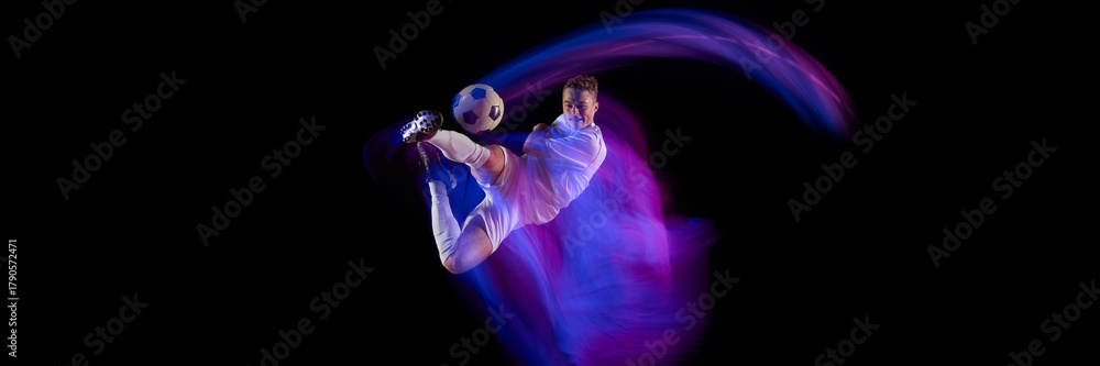 Fototapeta premium Soccer player performing overhead kick with dynamic neon trail on black background. Concept of ambition, skill, courage, and drive in sport, fitness promotion, and creative advertising visuals. Banner