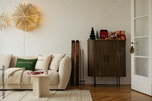 Festive living room with Christmas decorations, glowing star wall light, and wrapped gifts on a cabinet.