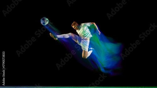 Quadro em tela Soccer player performing midair kick surrounded by glowing blue and green light motion