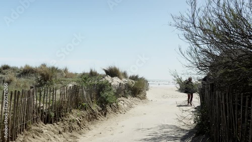 Person walking to beach through dunes on sunny summer day