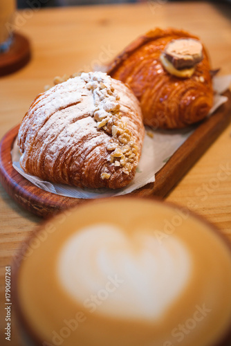 Fresh croissants with powdered sugar and cappuccino coffee in a cozy cafe