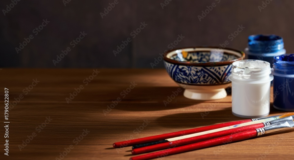 Obraz premium A close-up of traditional Asian ceramic bowls and paint jars with brushes on a wooden surface