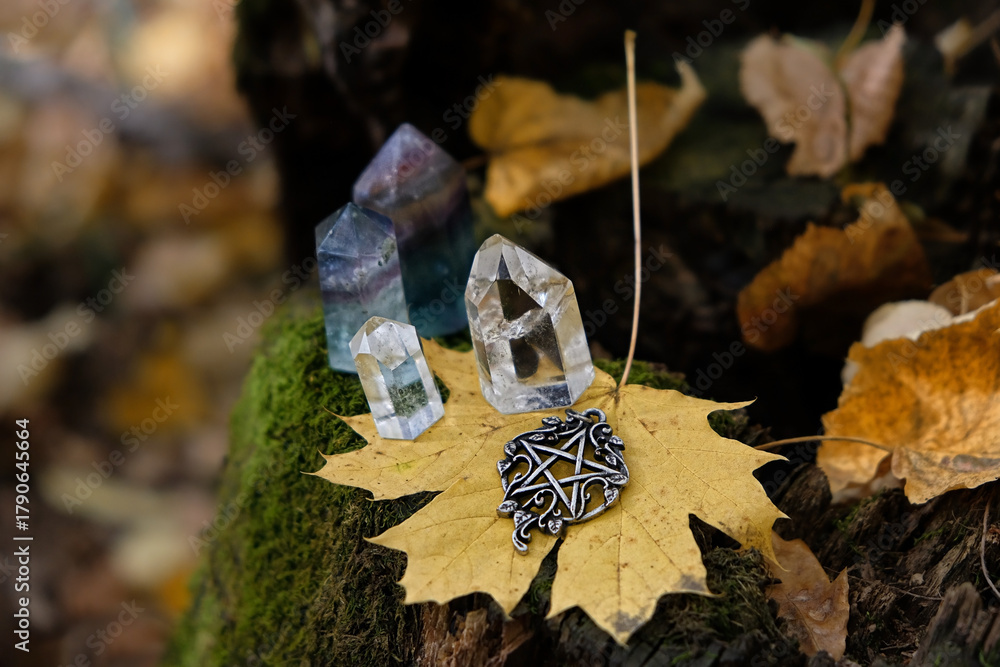 Naklejka premium pentacle amulet, quartz crystals, fallen leaves close up on tree stump, autumn forest natural background. minerals for Magic crystal Ritual. Witchcraft, spiritual esoteric ceremony. Lithotherapy.