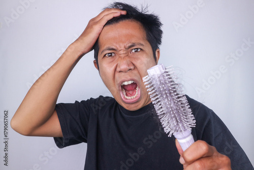 Tableau sur toile funny expression of angry asian man holding comb, problem hair, hair loss