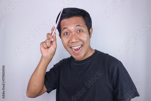 Cheerful expression of asian man brushing her hair, isolated on white background. Hair care concept