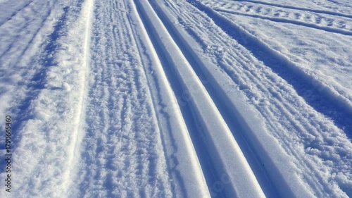 Prepared cross country ski track and snowmobile traces running through a vast snowy landscape toward a distant