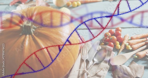 Displaying pumpkin left-of-center on blue table, tied-cutlery-napkin, tomatoes, carrots, DNA-helix