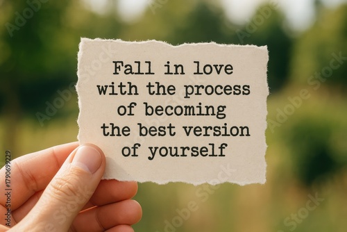 Person's hand holding a torn paper with the quote 