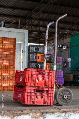 Fototapeta Hand truck with stacked plastic crates in a warehouse