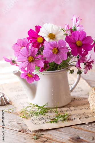 Vaso di fiori di cosmea rosa e bianco sopra spartiti di musica sfocati