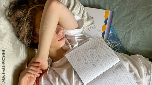 Tired Teenager Lying In Bed With School Notebook And Hand Over Face. Concept Of Academic Burnout, Student Stress, Homework Overload, Mental Fatigue In Teens, And Education Pressure Visuals