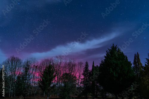 Star filled night sky illuminated by the bright magentas of the Aurora Borealis over the Dordogne region of France