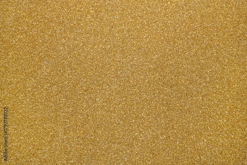 Golden glitter textured paper showing gleaming particles, suitable for festive, celebration, or luxurious concepts