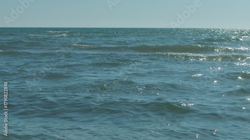 Gentle turquoise waves of the sea in the rays of the evening sun against a blue sky