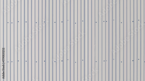 A close up of a white metal corrugated wall with fasteners evenly spaced in a repeating pattern