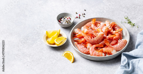 Fresh raw shrimp with lemon served on a plate. Light grey background. Copy space.