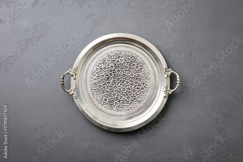 Antique silver serving tray featuring detailed floral design and decorative handles. Grey background. Copy space. Top view.
