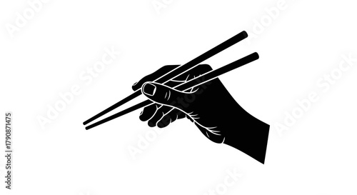 A hand skillfully holding a pair of black chopsticks in silhouette